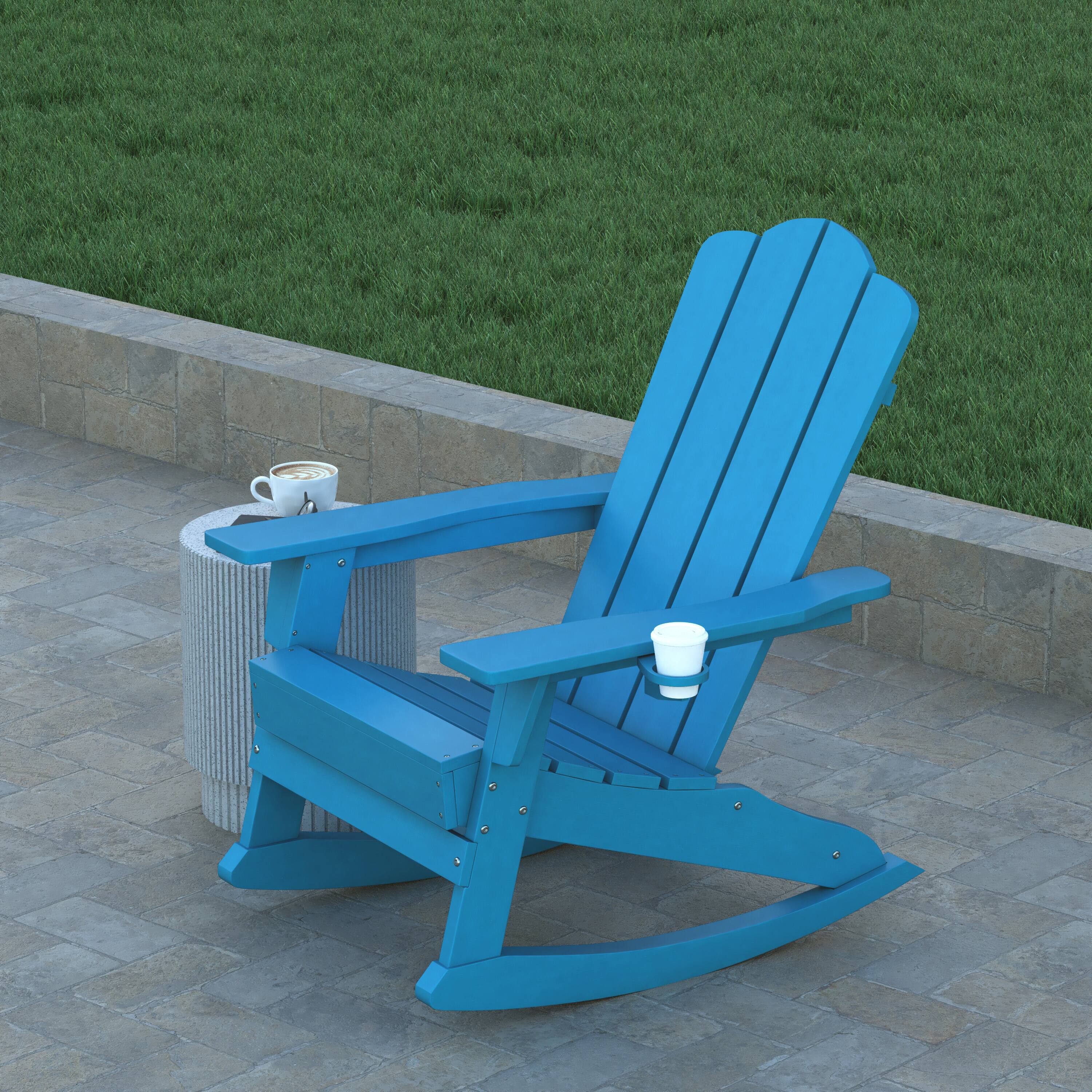Blue Adirondack rocking chair with a cup on a side table outdoors.