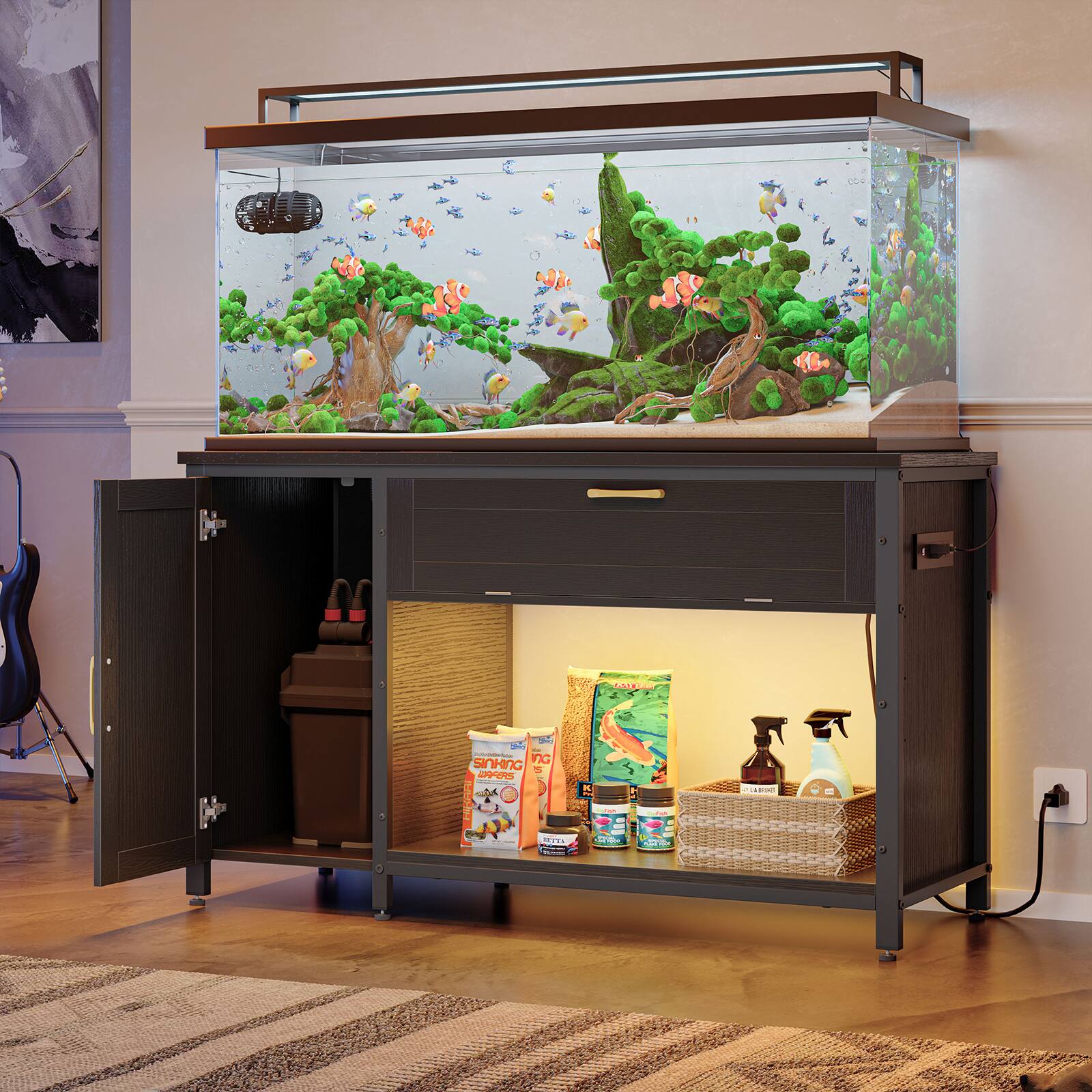 The image features a large aquarium with a variety of fish and plants. The aquarium is placed on a wooden stand, which also has a small cabinet underneath it. The cabinet contains several fish food containers and a cleaning spray bottle. The scene is set in a living room, with a guitar visible in the background.