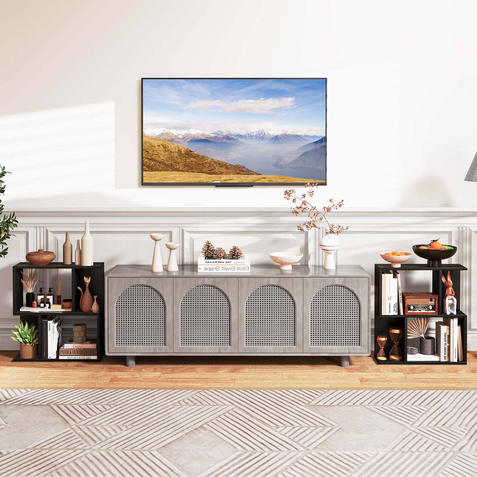 The image features a living room with a flat screen TV mounted on the wall. The room is decorated with various items, including a potted plant, a vase, and a bowl. There are also several books scattered around the room, and a remote control can be seen on a surface. The overall atmosphere of the living room appears to be cozy and inviting.