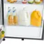 The image shows a refrigerator with a variety of drinks and food items. There are several bottles of juice, including a bottle of tomato juice, and a bottle of milk. Additionally, there are two bottles of soda and a bottle of wine. The refrigerator also contains a bowl of fruit, which includes apples and oranges. The arrangement of these items suggests that the refrigerator is well-stocked and ready for use.