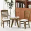 The image features a wooden dining table with two wooden chairs placed around it. The table is adorned with a potted plant, a vase, and a coffee cup. There are also several books on the table, adding a touch of intellectual ambiance to the scene. The arrangement of the table, chairs, and decorative items creates a cozy and inviting atmosphere for a meal or a casual gathering.