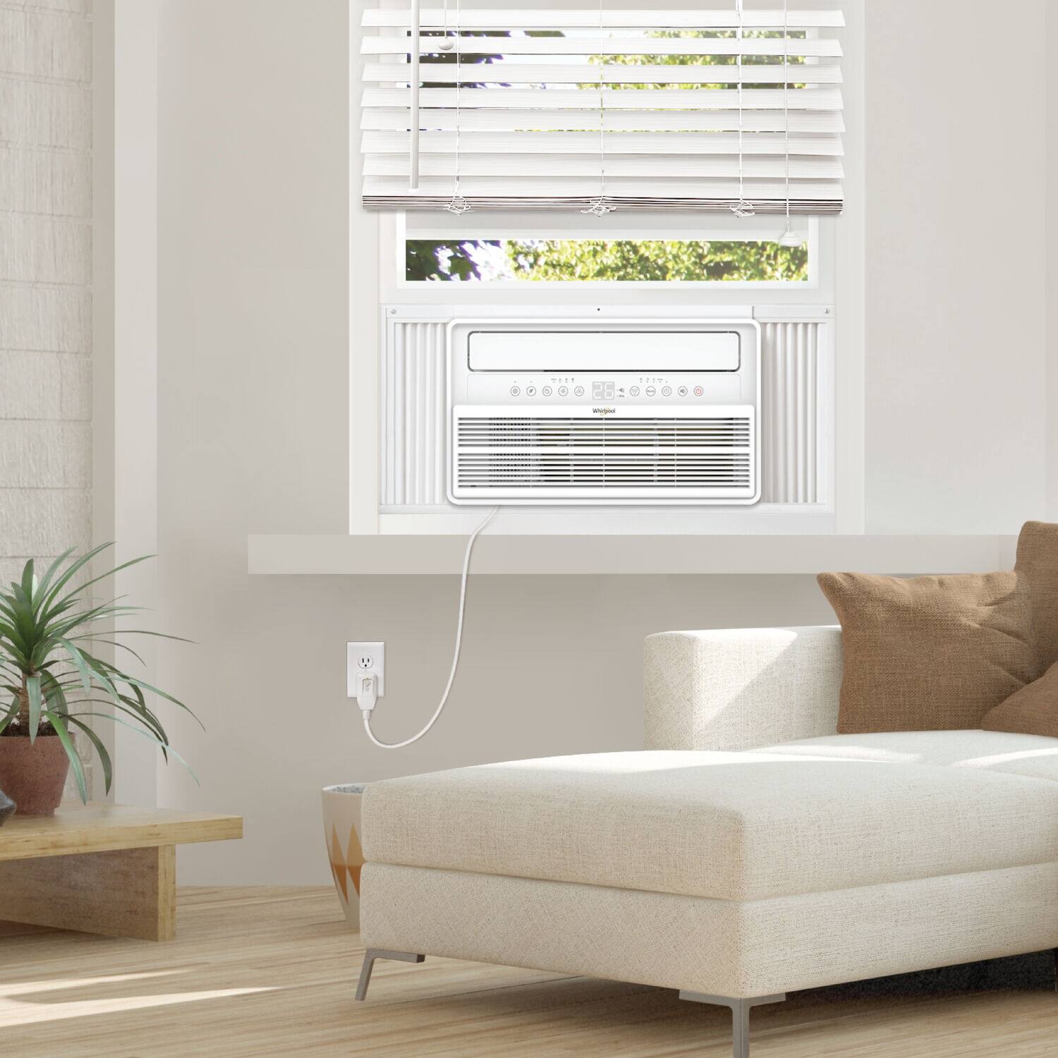 1. A small white couch is in the living room.
2. A window air conditioner is in the window.