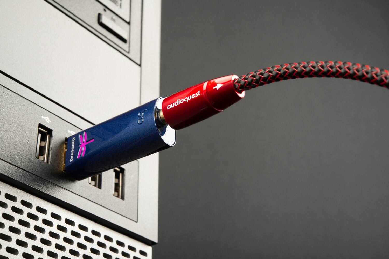 The text on the image reads "DR DRAGONFLY * bo audioquest." This is likely a product name or brand name for an audio device, such as a sound card or headphones. The red and black cords are connected to the device, which is plugged into a computer.