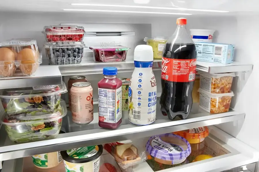 The refrigerator contains a variety of food items and drinks, including a bottle of soda, milk, and juice. The refrigerator is full, with items occupying all the shelves. The items are organized in a way that makes it easy to find and access what is needed. The refrigerator is a convenient and efficient way to store and preserve food and beverages, ensuring that they remain fresh and safe to consume.
