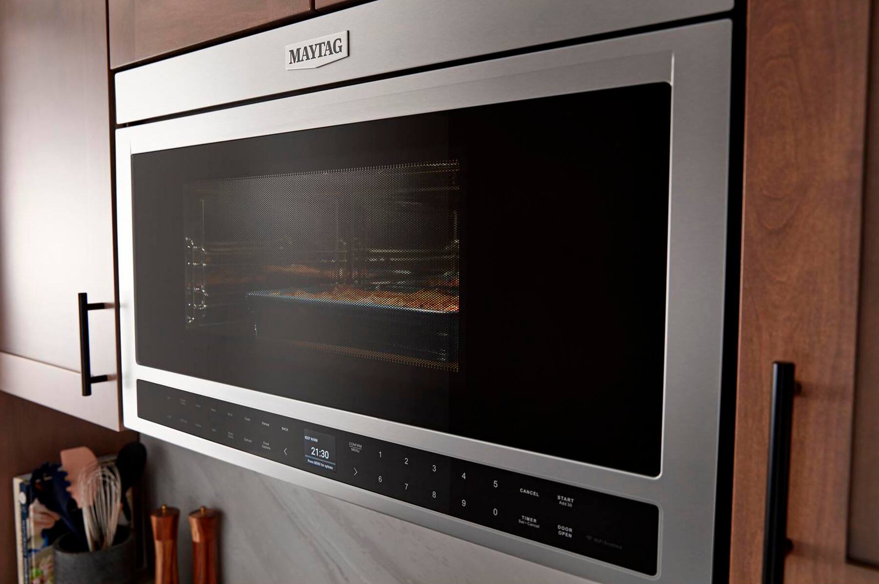 The text on the image reads "MAYTAG 21:30 - > 1 6 2 7 3 8 4 9 5 0 CANCEL TIMER Set-Cancel START MEW DOOR OPEN."