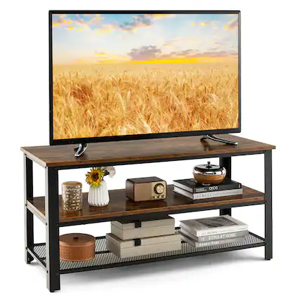The image features a television sitting on a wooden stand, which has a shelf underneath. On the shelf, there are various items, including a vase, a clock, and a bowl. Additionally, there are several books placed on the shelf. The television is displaying a picture of a field of wheat, creating a serene and peaceful atmosphere in the room.