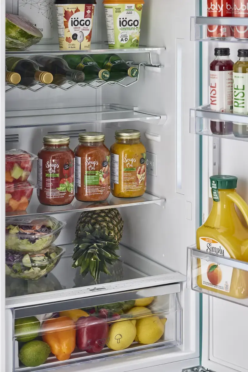 The refrigerator is stocked with a variety of food items, including fruits, vegetables, and beverages. The fruits include apples, oranges, and bananas, while the vegetables consist of broccoli and carrots. There are also several bottles of juice and water, as well as a bowl of fruit salad. The refrigerator is well-organized, with the food items placed in different compartments, making it easy to find and access the desired items.