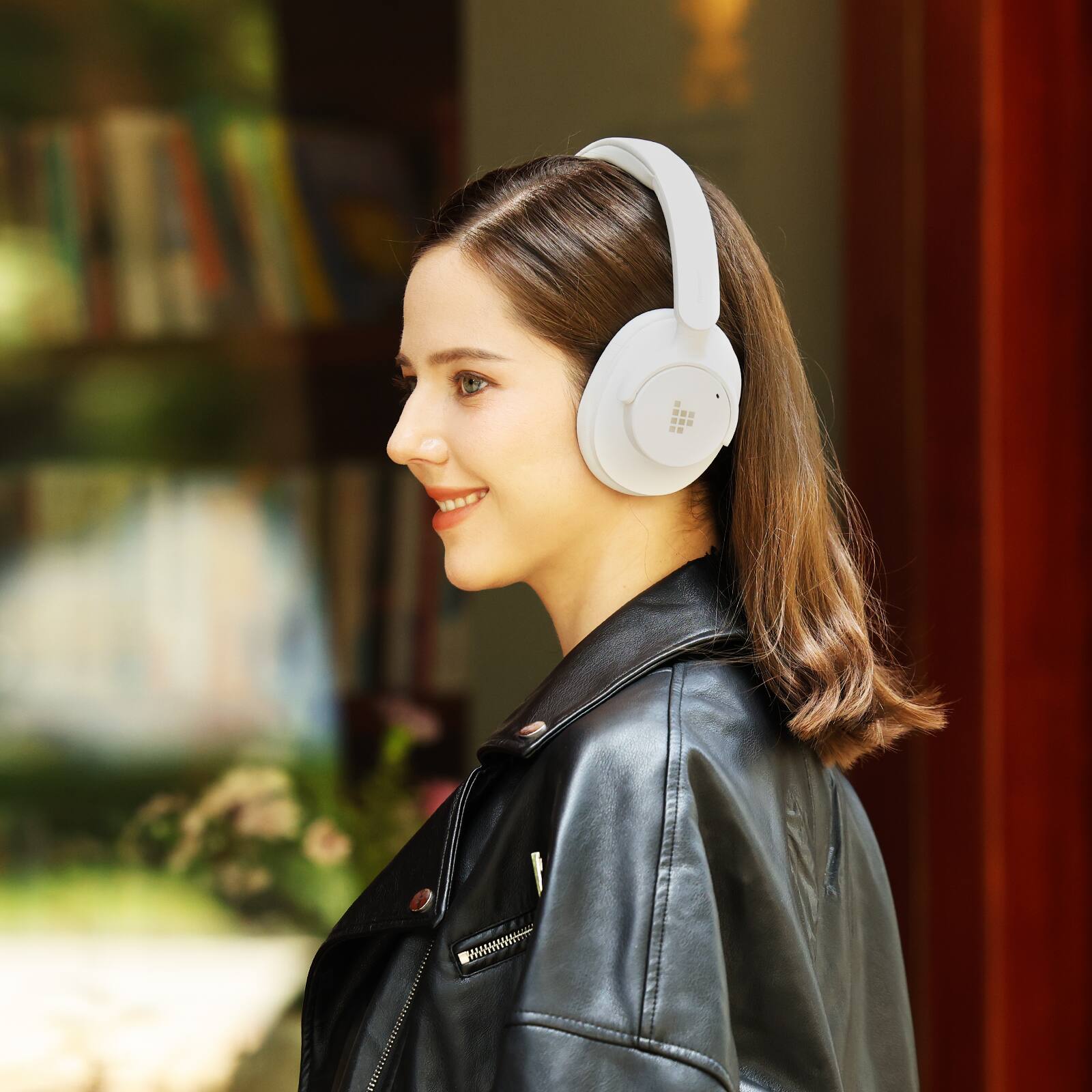 A woman wearing a black leather jacket and headphones is smiling.