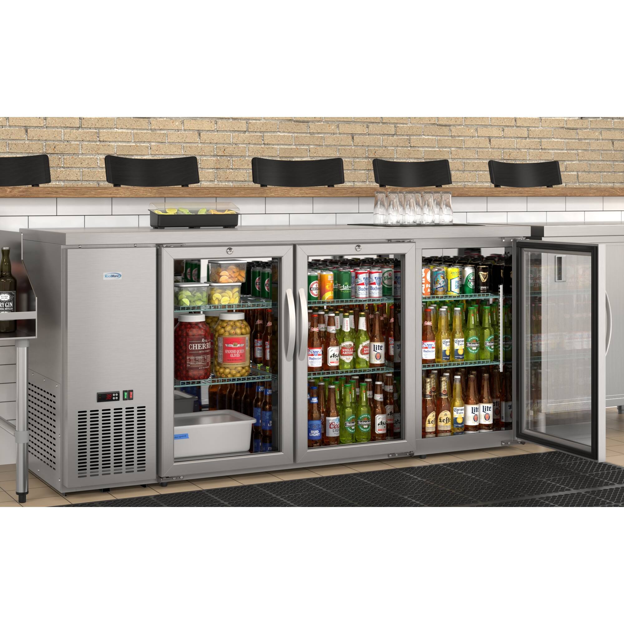 The image shows a refrigerator with its doors open, revealing a variety of drinks inside. There are multiple bottles of beer and other beverages, as well as some cups. The refrigerator is located in a room with a brick wall, and there are chairs nearby. The scene appears to be a bar or a similar establishment where people can enjoy their drinks.