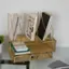 The image shows a desk with a variety of items on it. There is a bookshelf with several books, including a book with a colorful cover. The books are arranged in a way that they are standing up, creating an organized and visually appealing display. In addition to the books, there is a small tray with a remote control and a calculator on it. The desk also has a potted plant, adding a touch of greenery to the space.