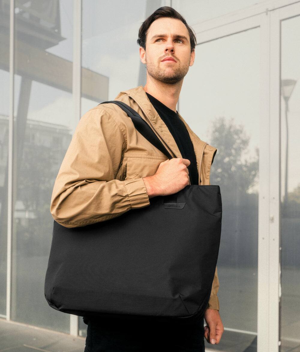 Angle. ALPAKA - Elements Tote 20L Laptop Tote Bag with Padded 16" Sleeve,Open Top with Magnetic Closure - Black Axoflux 210D.