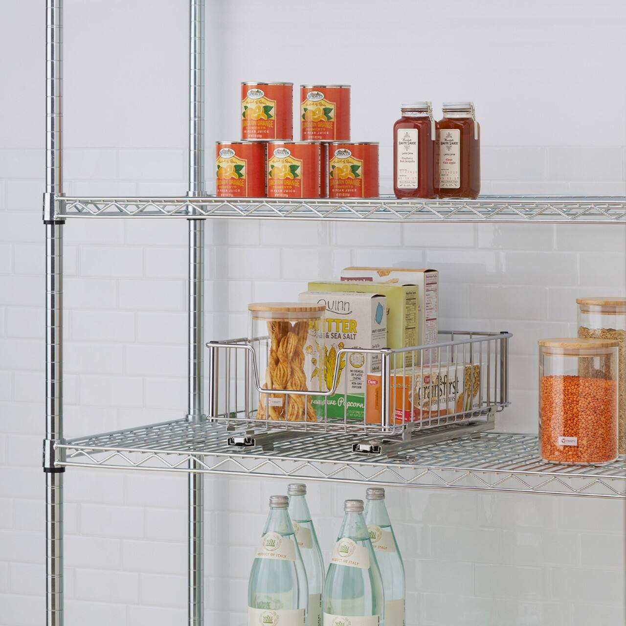 The image features a shelf with various food items and bottles. There are two bottles of water, one on the left side and the other on the right side of the shelf. In addition, there are three bottles of orange juice, with one located in the middle, another on the left side, and the third on the right side of the shelf. 

There are also two cans of food, one on the left side and the other on the right side of the shelf. A bowl is placed on the left side of the shelf, and a spoon is located near the center of the shelf. The shelf is filled with various food items, creating a diverse and organized display.