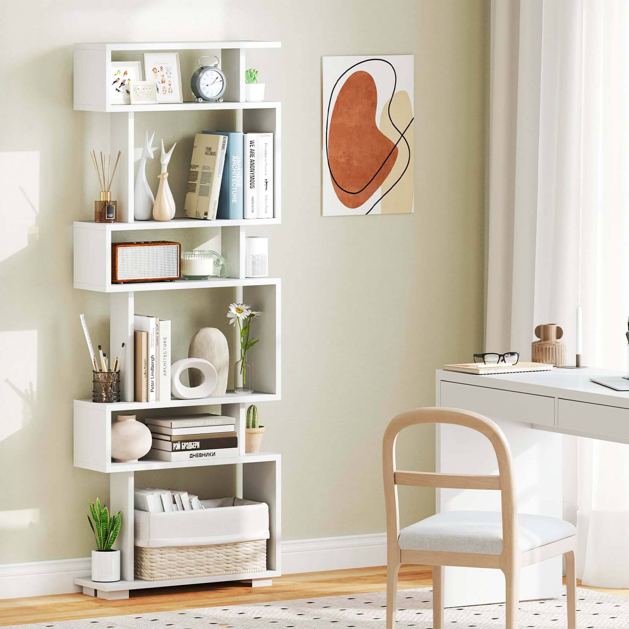 The image features a white shelf with various items on it, including books, a clock, and a vase. The shelf is placed in a room with a chair, a desk, and a window. The room also has a wall with a painting on it. The arrangement of the items on the shelf creates a cozy and organized atmosphere in the space.