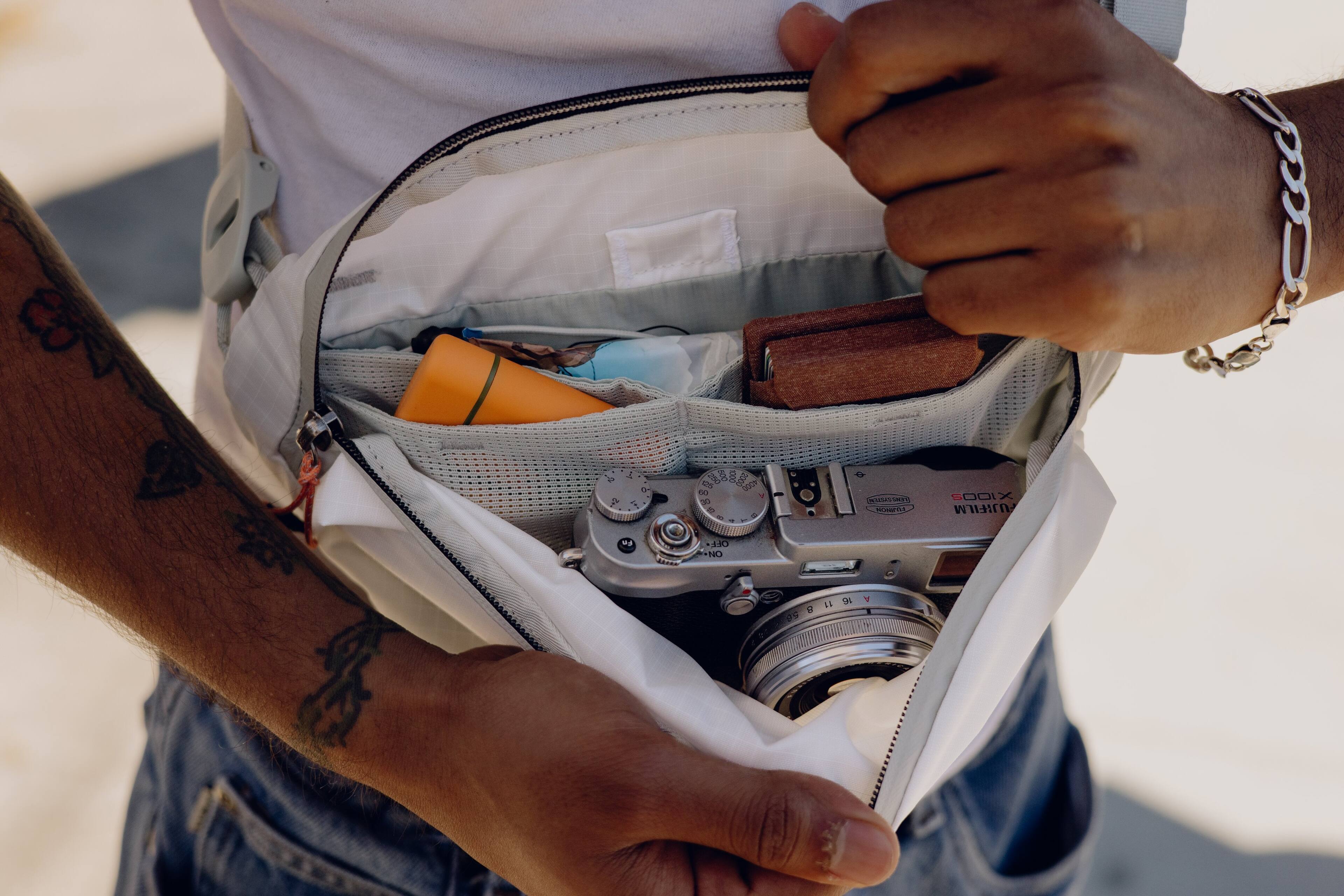 A man is holding a Fujifilm camera in his hand.