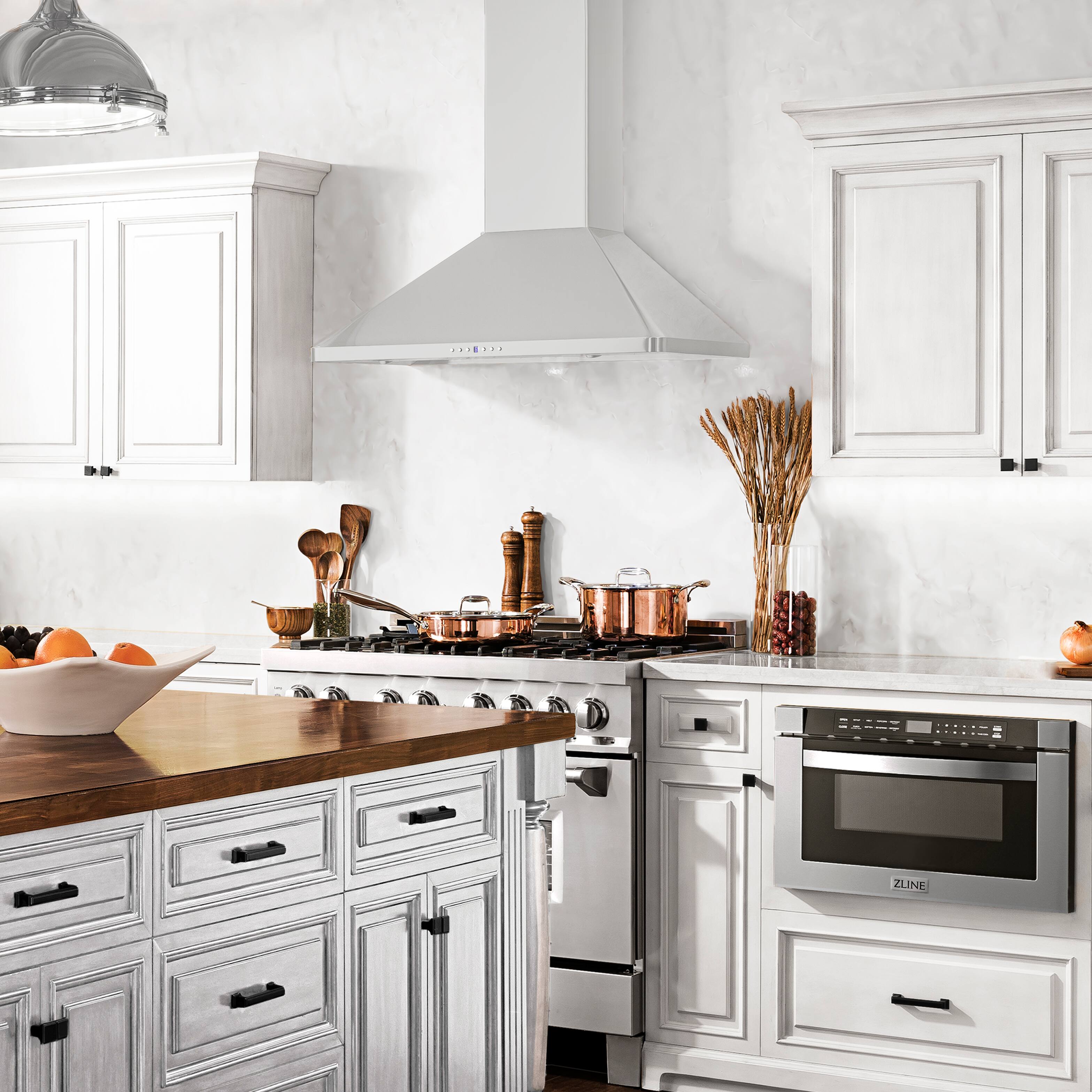 The image features a kitchen with white cabinets and a stove top oven. The oven is positioned next to a counter with a bowl of fruit, including oranges and apples. The kitchen also has a sink and a microwave. The overall design of the kitchen is modern and clean, with a focus on functionality and aesthetics.