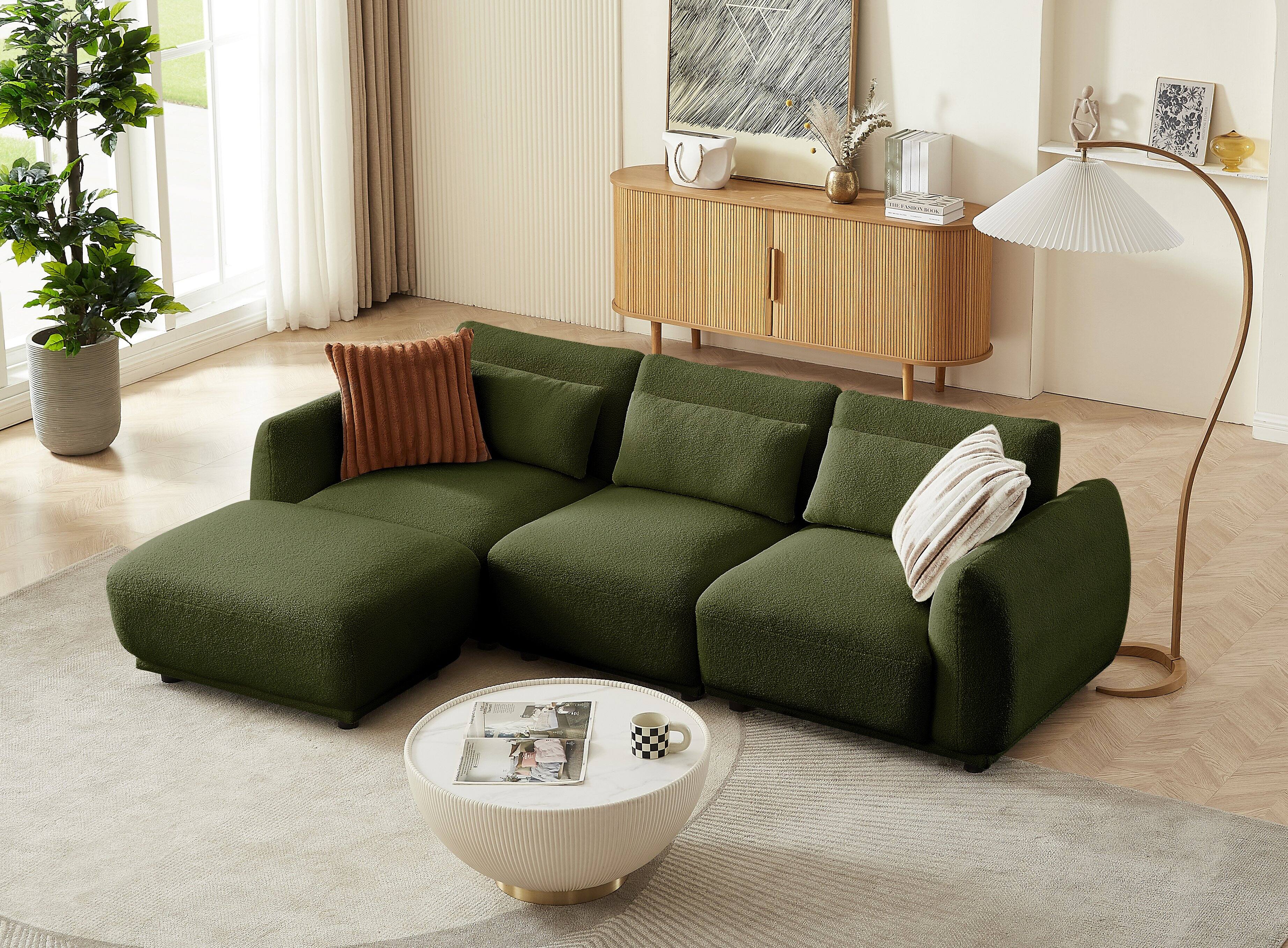 The image does not contain any text. It shows a modern living room with a green sofa, a marble coffee table, a wooden cabinet, and various decorative items.
