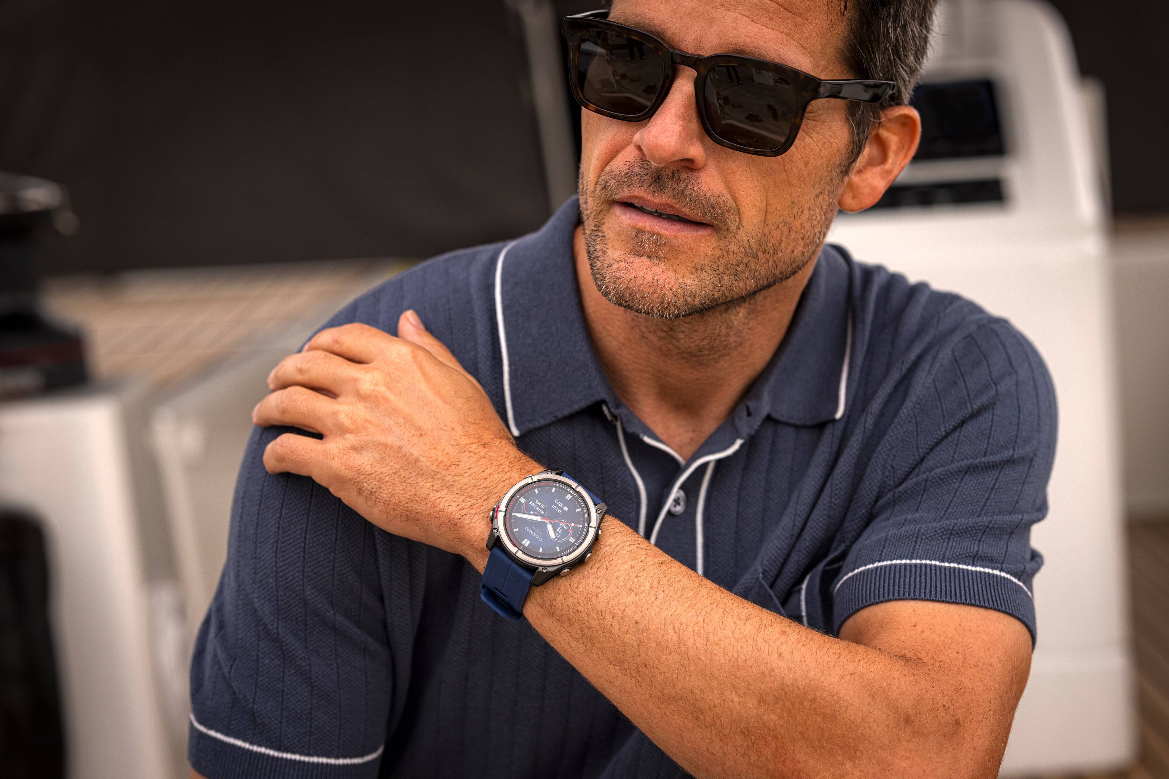 The man is wearing a blue striped shirt and sunglasses.