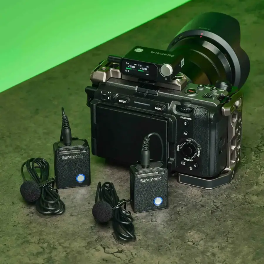 The image features a camera with a microphone attached to it. The camera is placed on a table, and there are three microphones in the scene. The microphones are positioned in front of the camera, with one on the left side, one in the middle, and one on the right side. The camera is likely being used for a recording session or a live event, as it is equipped with the necessary audio equipment.