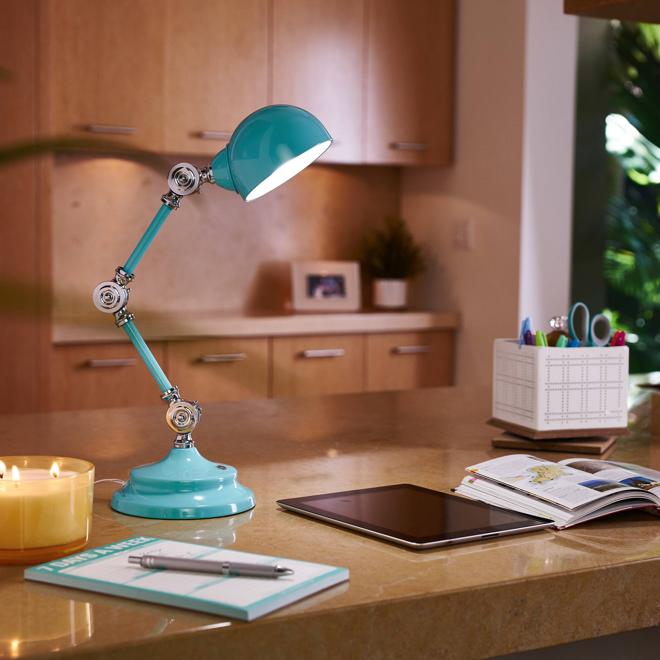 I'm sorry, but I cannot group or correct the text "AREEA TSAIS" as it does not seem to be related to the image content. The image features a desk with a lamp, a tablet, a book, and a candle.