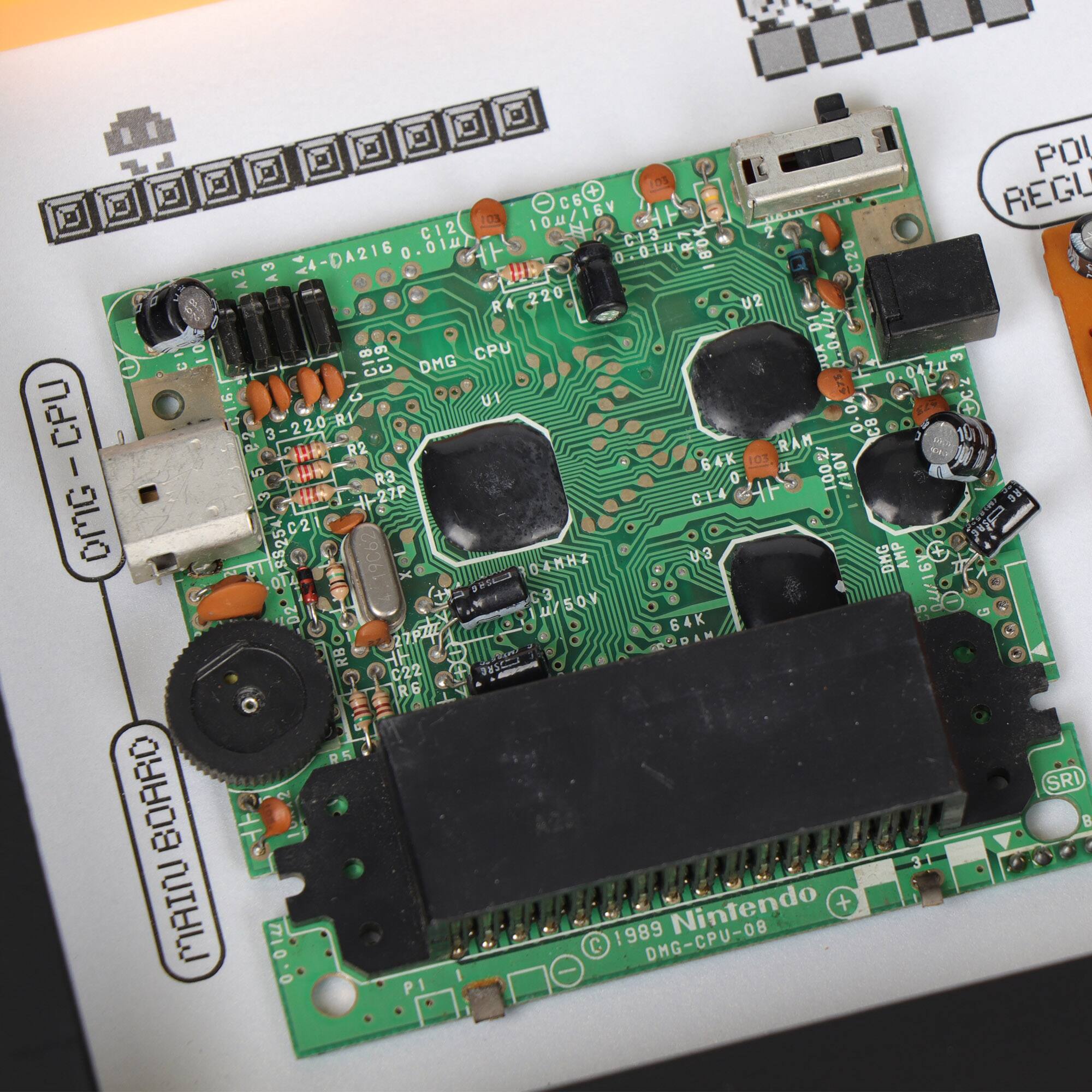 Sure, here is the corrected and grouped text from the image:

---

**Main Board**

**DMG-CPU-08**

**Nintendo**

**1989**

**DMG-CPU-08**

**POI 10s + REGU 10u/16V O 10% C12 N C13 2 DA216 0 1 00U.0 0.8 2 3 C20 R4 220 U2 C0 DMG CPU K JUA 3 a 0 7 U1 YO CPU + 3-220-RI 0. CB HR R2 R 64K 6 1OS : I HN i 100 AGEA R3 HE 27P CE DX aWO C2 ERON 8525 O4MHZ U3 DMG AMP 6Y* O 91/770 2 u/SOV 64K 27PZZ ODAM RB C22 0 R6 R5 SRI BOARO B MAIN Nintendo + C 1989 DMG-CPU-08**

---

This text appears to be a combination of component labels and possibly a schematic or assembly instructions for the Nintendo console.