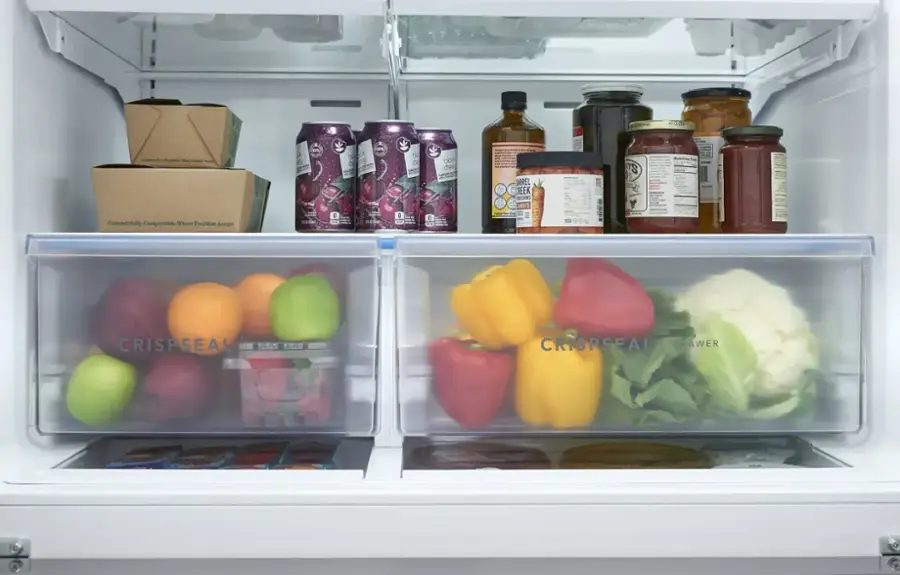 The image shows a refrigerator with two drawers filled with various fruits and vegetables. The text on the image indicates that the containers are commercially compostable, meaning they can be composted at facilities that accept them. The fruits and vegetables are organized in the drawers, making it easy to access and consume them.