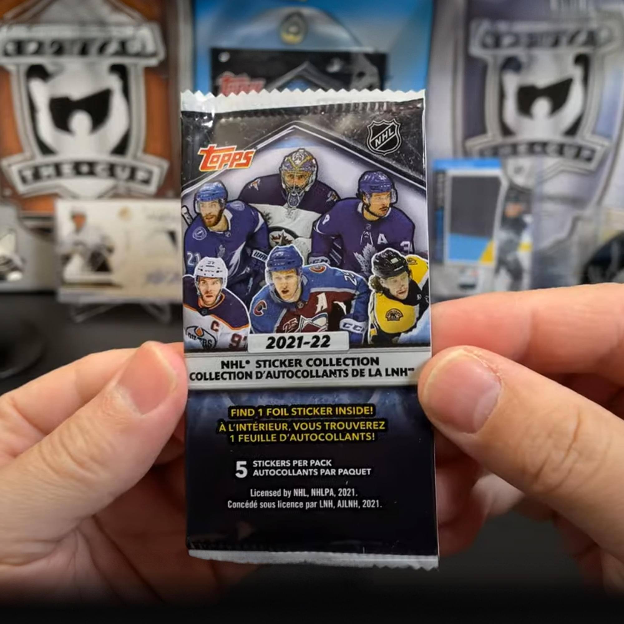 Sure, here is the corrected and grouped text from the image:

---

**Topps**

**2021-22 NHL® STICKER COLLECTION**

**COLLECTION D'AUTOCOLLANTS DE LA LNH**

**FIND 1 FOIL STICKER INSIDE!**

**À L'INTÉRIEUR, VOUS TROUVEREZ 1 FEUILLE D'AUTOCOLLANTS!**

**STICKERS PER PACK**

**AUTOCOLLANTS PAR PAQUET**

**5**

**Licensed by NHL, NHLPA, 2021.**

**Concéder sous licence par LNH, AJLNH, 2021.**

---