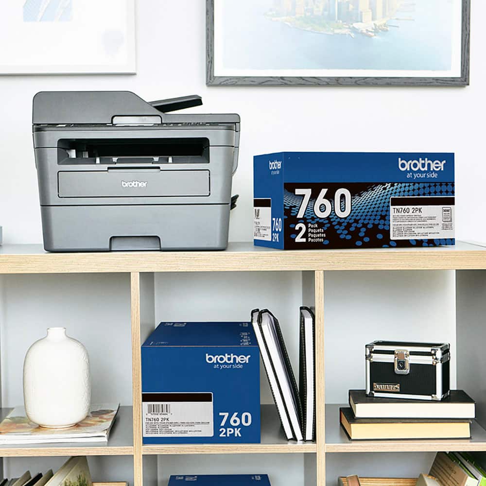 The image shows a shelf with a printer and various items. There are two boxes of Brother ink cartridges, one of which is 760 2PK, and a printer on the shelf. Additionally, there are several books and a vase on the shelf. The scene suggests that the printer is ready to be used, and the ink cartridges are readily available for printing.