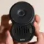 The text on the image reads "9 DO NOT TAMPER pura SCENT SMART pura." This suggests that the person holding the black object is being reminded not to tamper with it, and that it is a scent smart device made by pura.