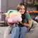 The image shows a woman sitting on a chair and holding a pink stuffed animal, which is a Nintendo character. The text on the image reads "6 C Nintendo/HAI HAL Laboratory. Inc." This suggests that the stuffed animal is a product of Nintendo and HAI HAL Laboratory, Inc.