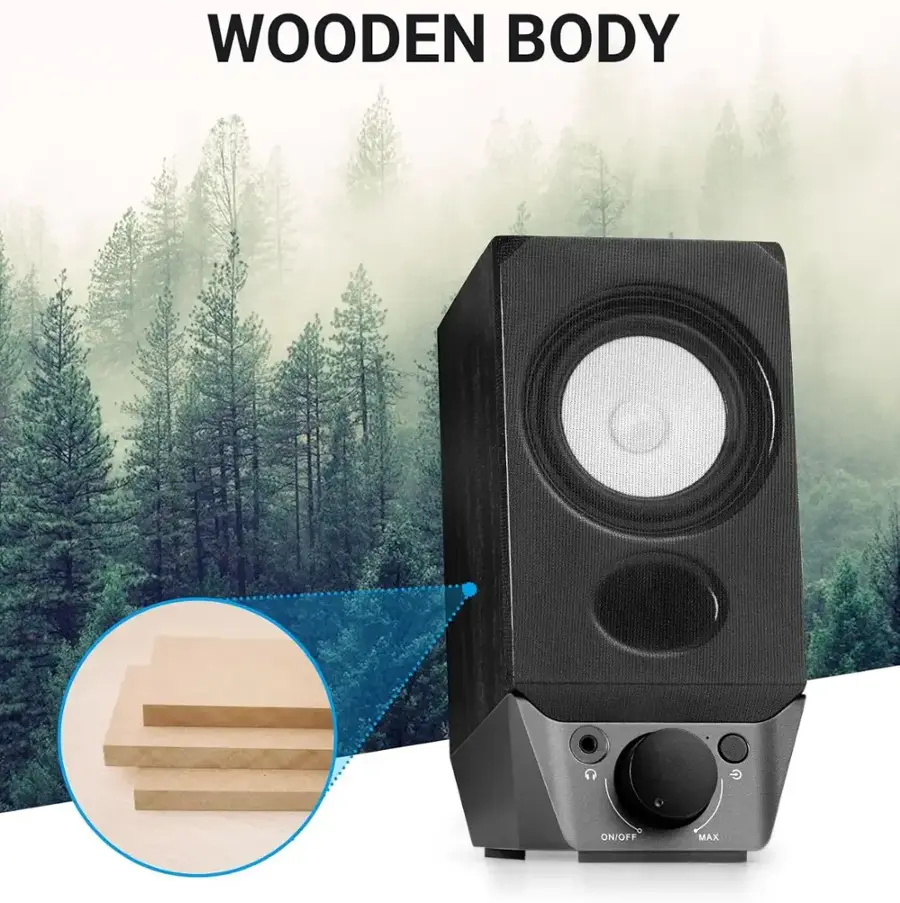 The image features a speaker with a wooden body and a G on/off switch. The speaker is placed on a wooden table, and there is a close-up view of the speaker's front. The scene also includes a forest in the background, adding a natural touch to the setting.