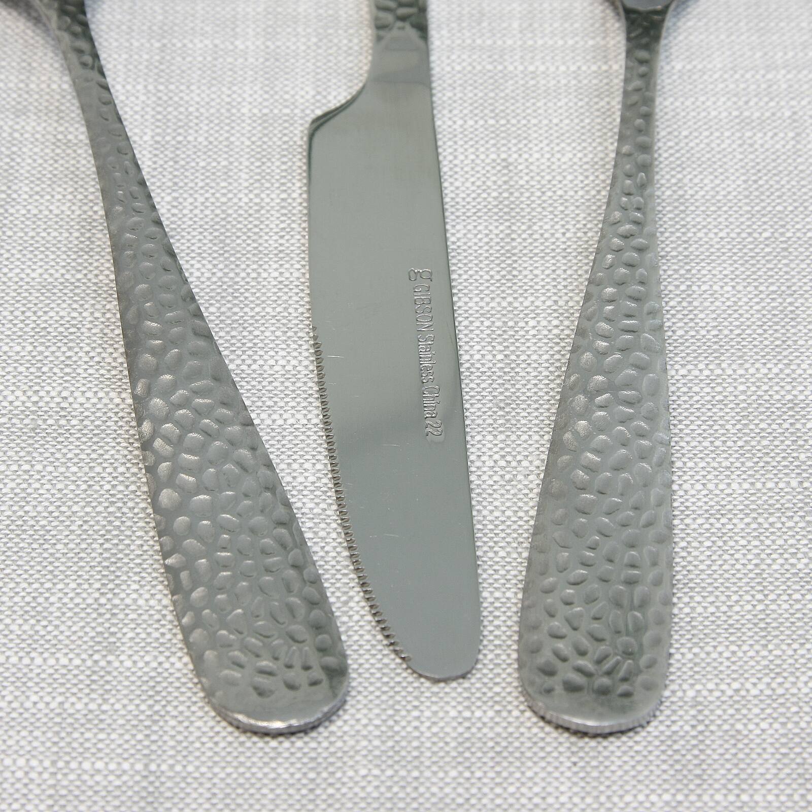 The image shows a table with three knives and a fork. The knives are made of stainless steel and have a unique design on them. The fork is also made of stainless steel and is placed next to the knives. The table is covered with a white cloth, and the knives and fork are arranged in a way that they are easily accessible for use.