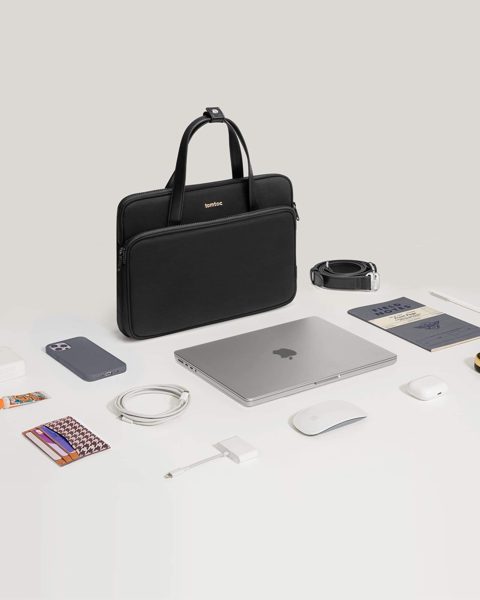 The image shows a black laptop, a mouse, a cell phone, and a wallet on a table.