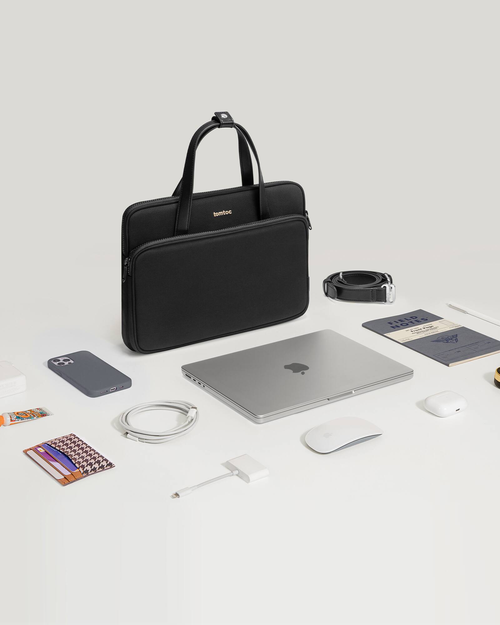The image shows a black laptop, a mouse, a cell phone, and a wallet on a table.