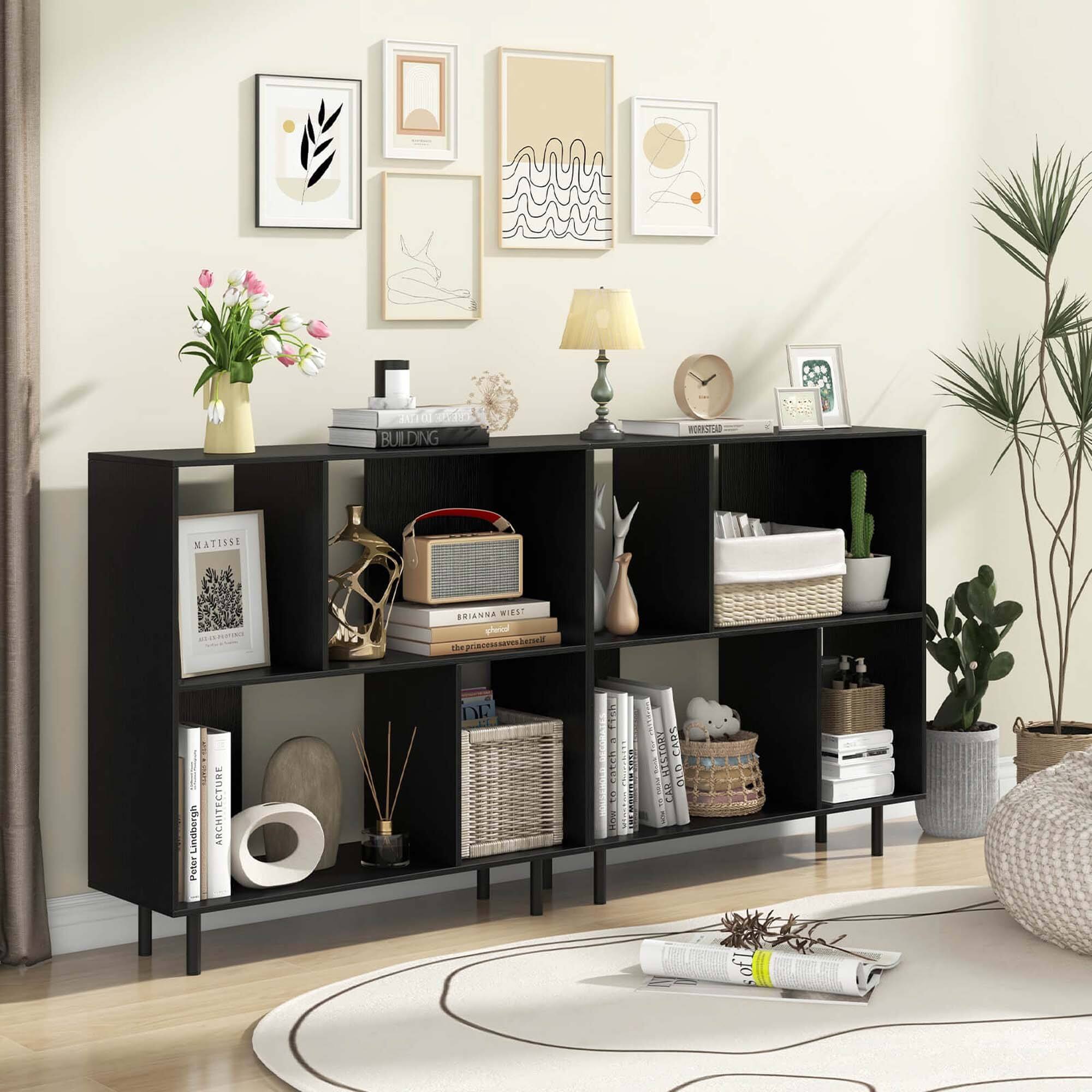 The image features a living room with a black bookshelf filled with various items. The bookshelf is placed on a hardwood floor and has a clock on top of it. There are several books on the shelves, as well as a vase and a potted plant nearby. The room also contains a couch and a bed, creating a cozy and comfortable atmosphere. The presence of the bookshelf and the various items on it suggest that the room is used for both relaxation and reading.