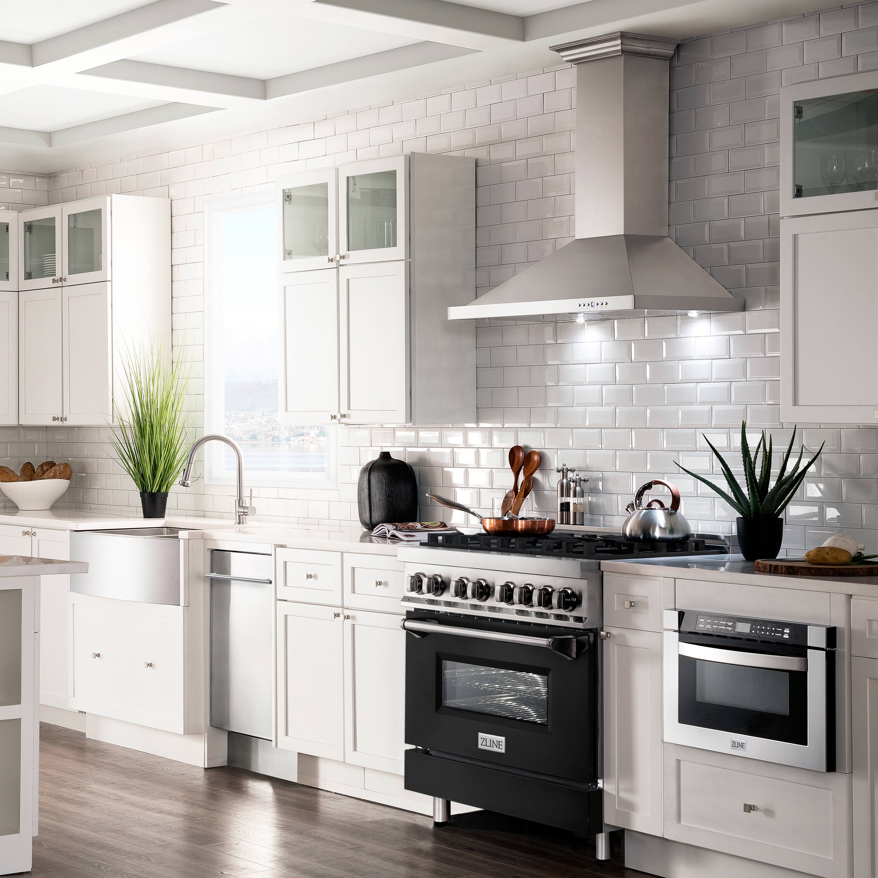 The image features a large, clean, and well-lit kitchen with white cabinets and a black stove top oven. The kitchen is equipped with a sink, a dishwasher, and a refrigerator. There are also various items on the countertops, such as a bowl, a potted plant, and a cup. The kitchen is well-organized and ready for use.