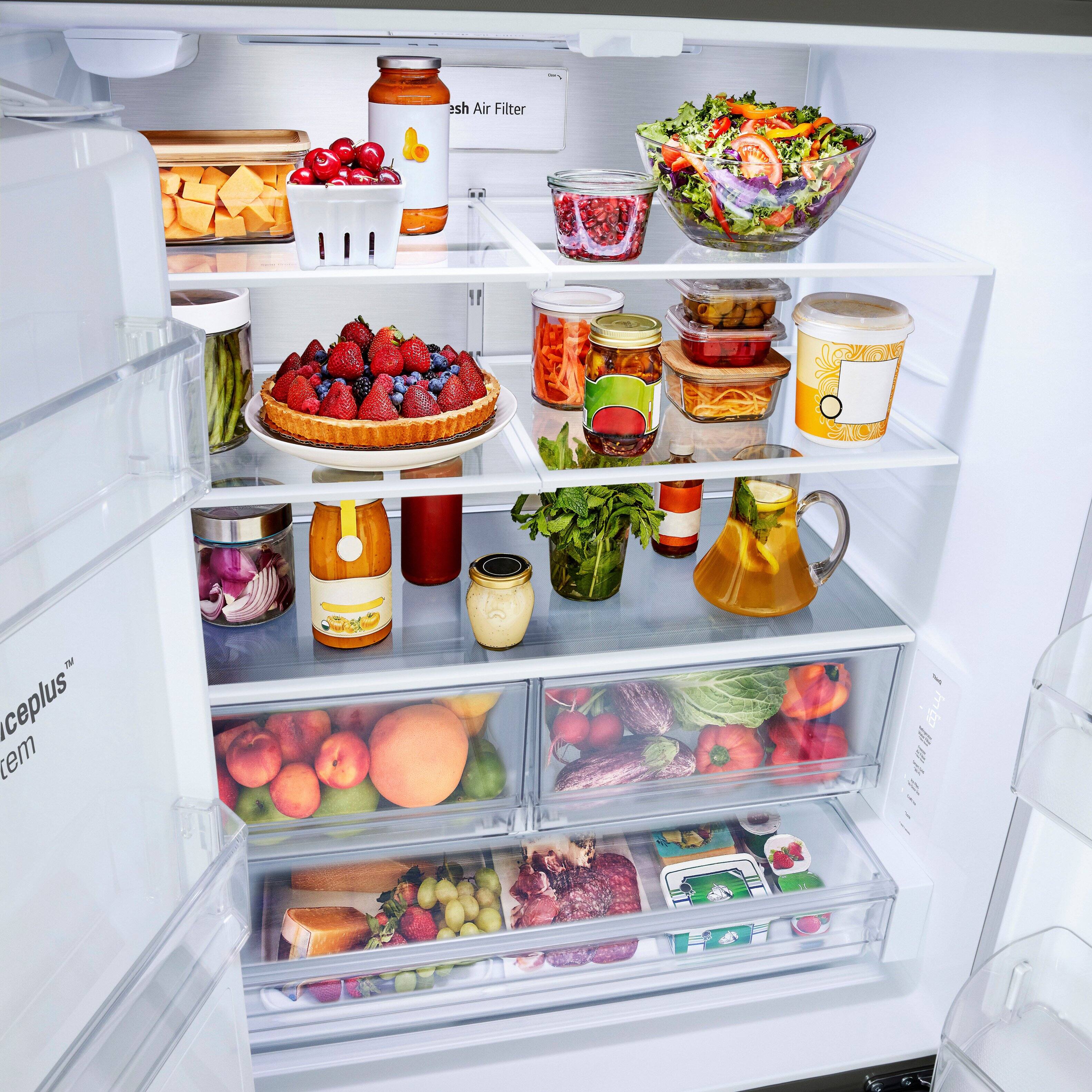 The image shows a refrigerator with its door open, revealing a variety of food items stored inside. There are several bottles, including a bottle of wine, and a bowl of fruit. The refrigerator is well-stocked with a diverse assortment of food, making it a convenient and accessible source of nourishment for the household.
