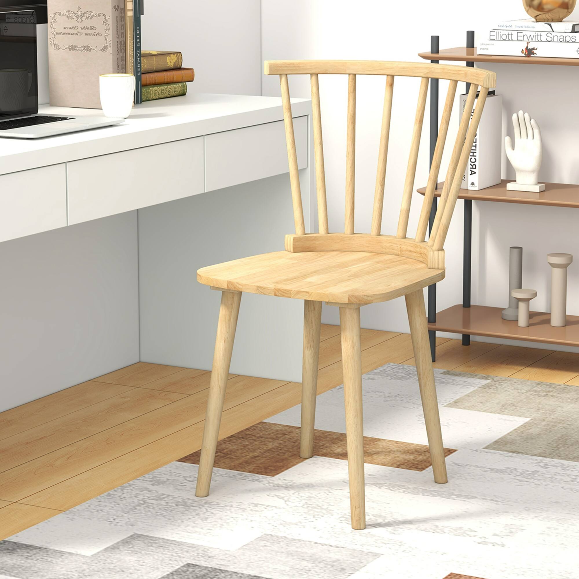 The image features a wooden chair with a brown seat, placed on a colorful rug. The chair is positioned in a room with a white countertop and a microwave nearby. There are also several books scattered around the room, some on the countertop and others on the floor. Additionally, there is a hand on a shelf, possibly a decorative or artistic element in the room.
