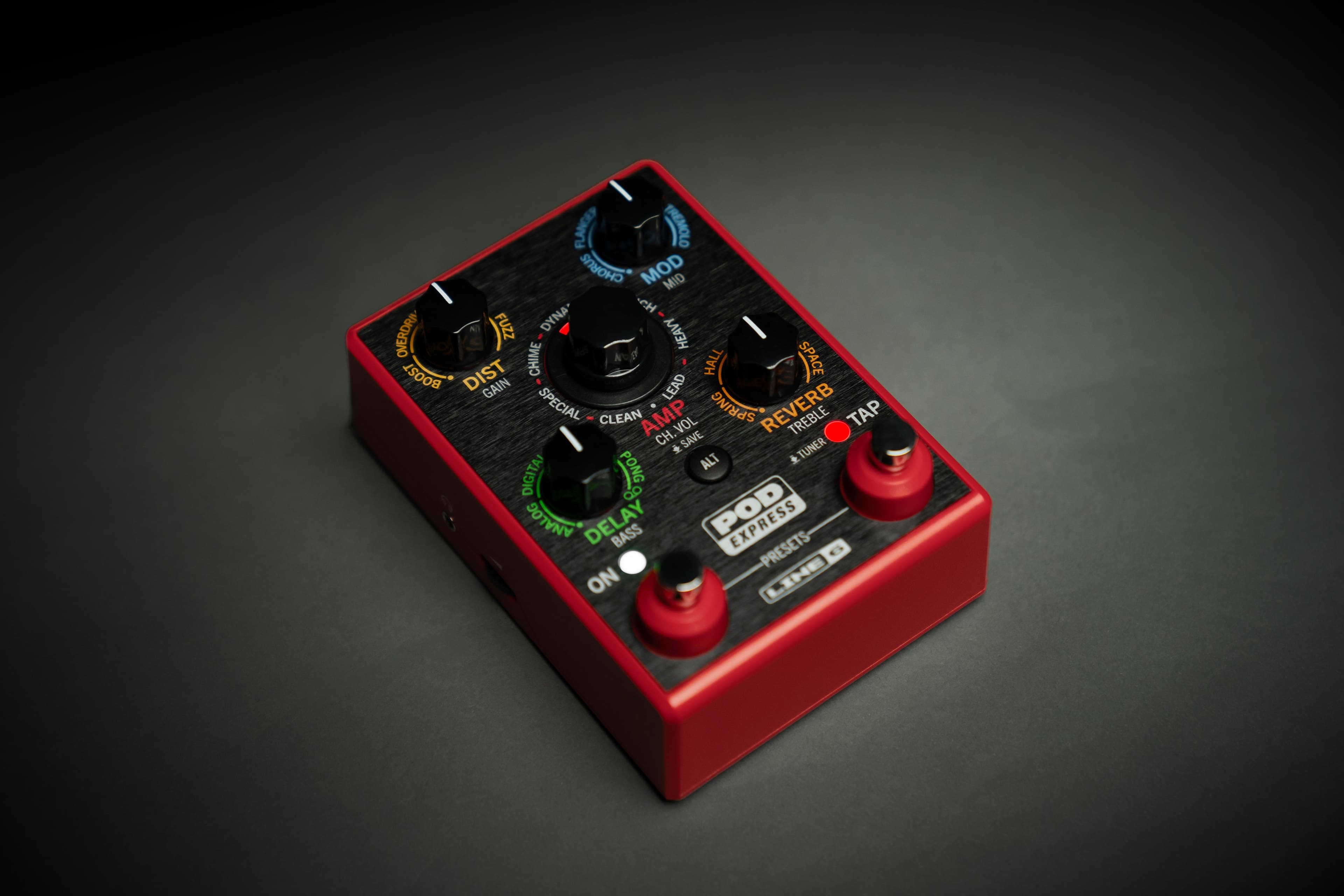 The image features a red electronic device with a variety of knobs and buttons on it. The knobs are labeled with different names, such as "Flange," "Tremolo," "Boost," "Overdrive," "Fuzz," "Dyna," "Heavy," "Lead," "Special," "Clean," "Amp," "Spring," "Reverb," "Treble," "Tap," "Vol," "Ch," "Save," and "Tuner." The device also has a digital display and an analog delay feature. The presence of these various knobs and buttons suggests that the device is a versatile and customizable electronic instrument, likely used for creating a wide range of sounds and effects.