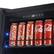 The image shows a refrigerator with a shelf containing several cans of Coca-Cola and Kaiser Beer. The cans are arranged in a row, with some positioned horizontally and others vertically. The refrigerator is filled with these beverages, offering a variety of options for consumption.