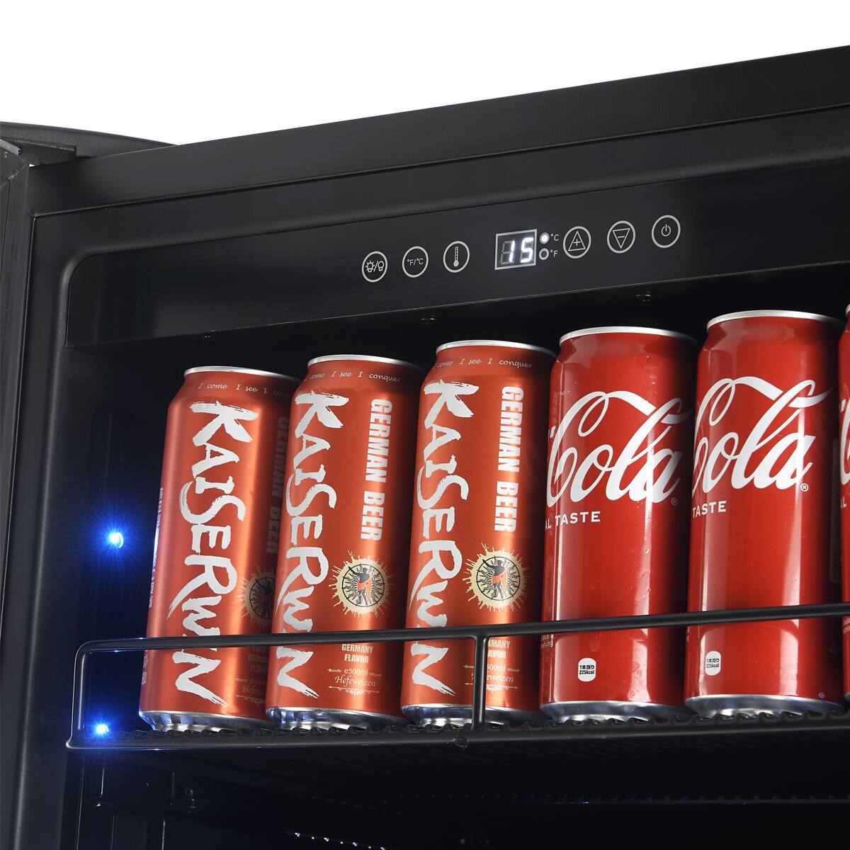 The image shows a refrigerator with a shelf containing several cans of Coca-Cola and Kaiser Beer. The cans are arranged in a row, with some positioned horizontally and others vertically. The refrigerator is filled with these beverages, offering a variety of options for consumption.