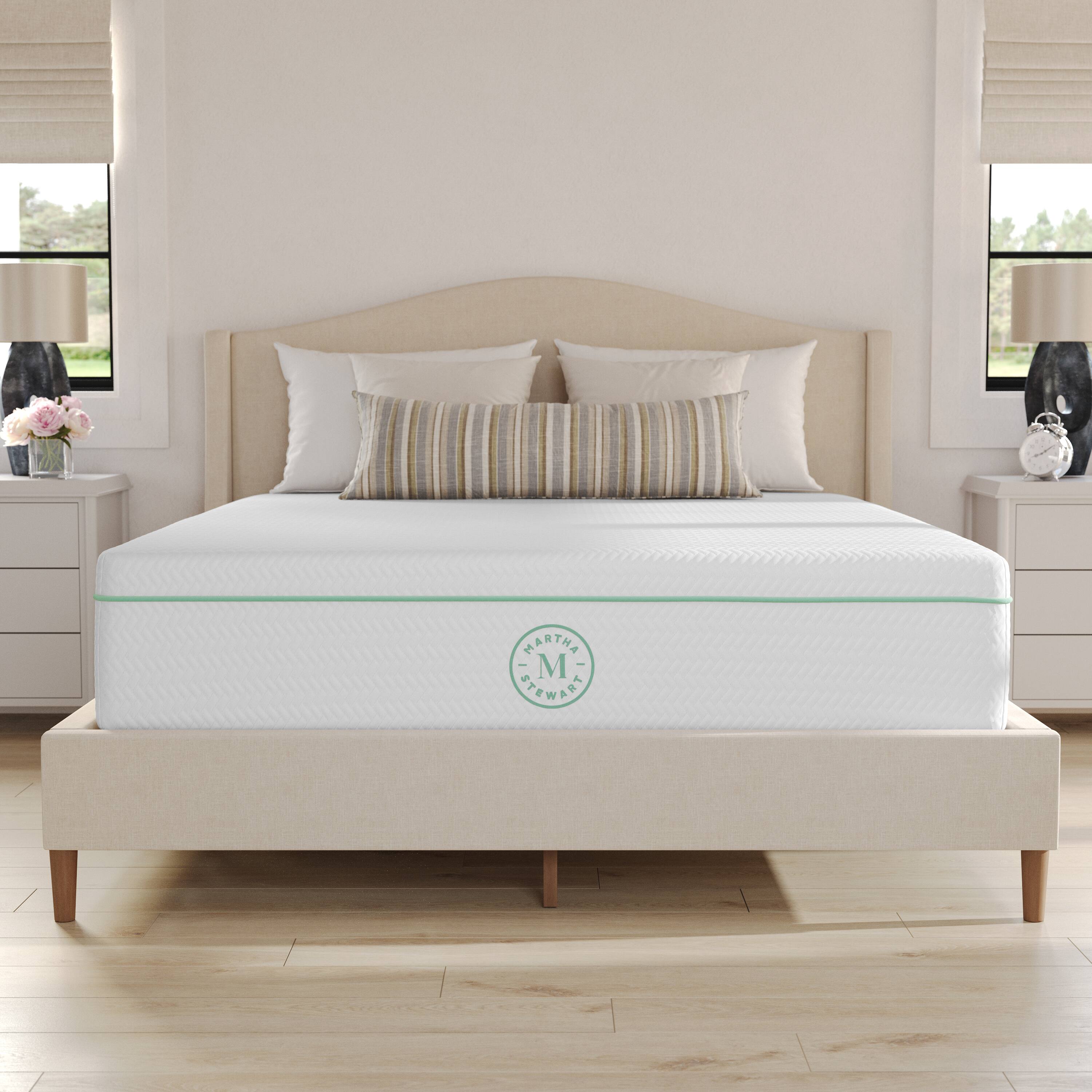 1. The bed is made with a white comforter and two pillows.
2. The bed has a green and white striped pillow.
3. The bed is in a bedroom with a wooden floor.
4. The bed is positioned in front of a window.
5. The bed is covered with a white comforter.