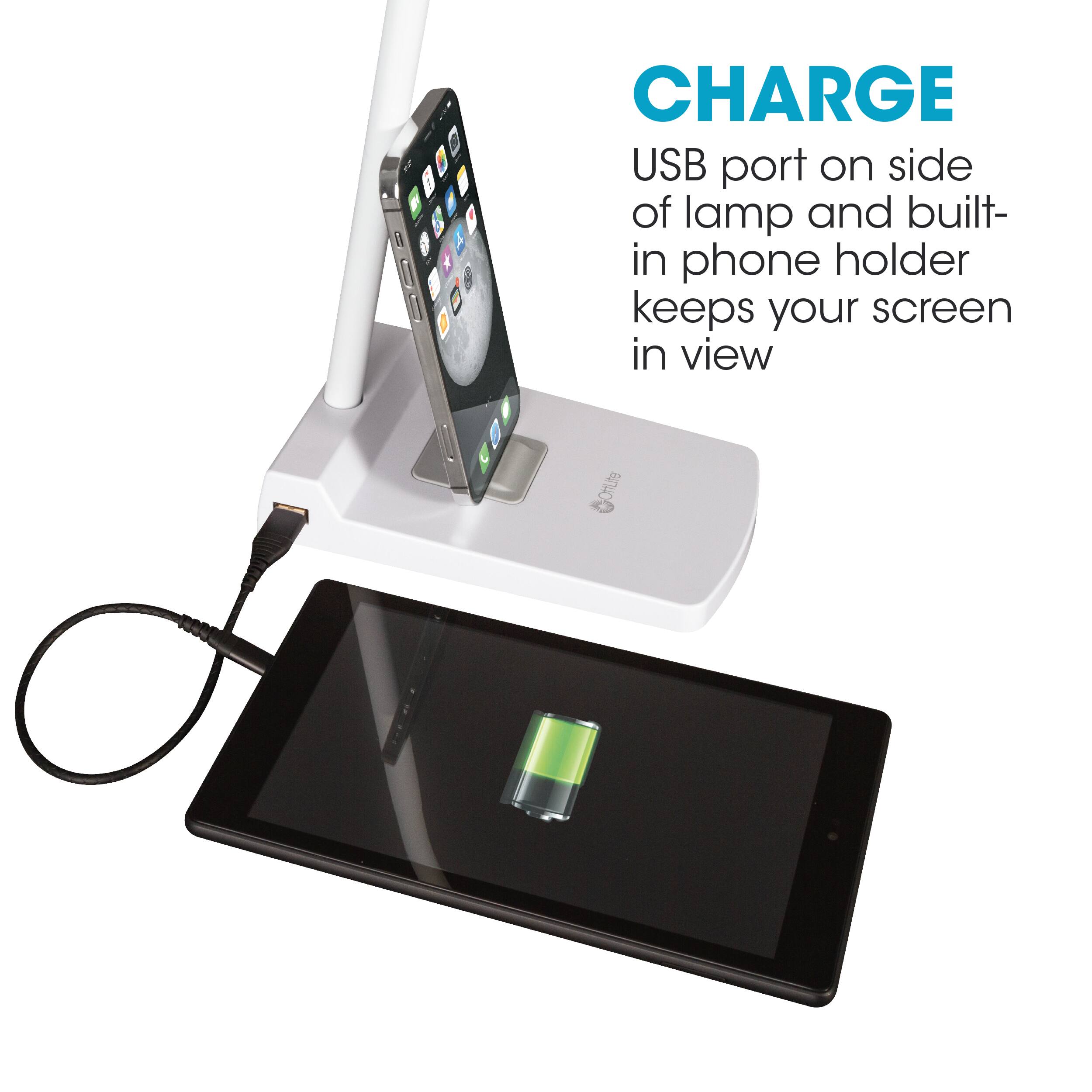 The image features a device with a USB port on the side of a lamp and a built-in phone holder. This setup allows you to charge your device while keeping the screen in view. The device is placed on a table, and there is a cell phone nearby, possibly charging or being charged. The image emphasizes the convenience of this setup for charging and viewing your device simultaneously.