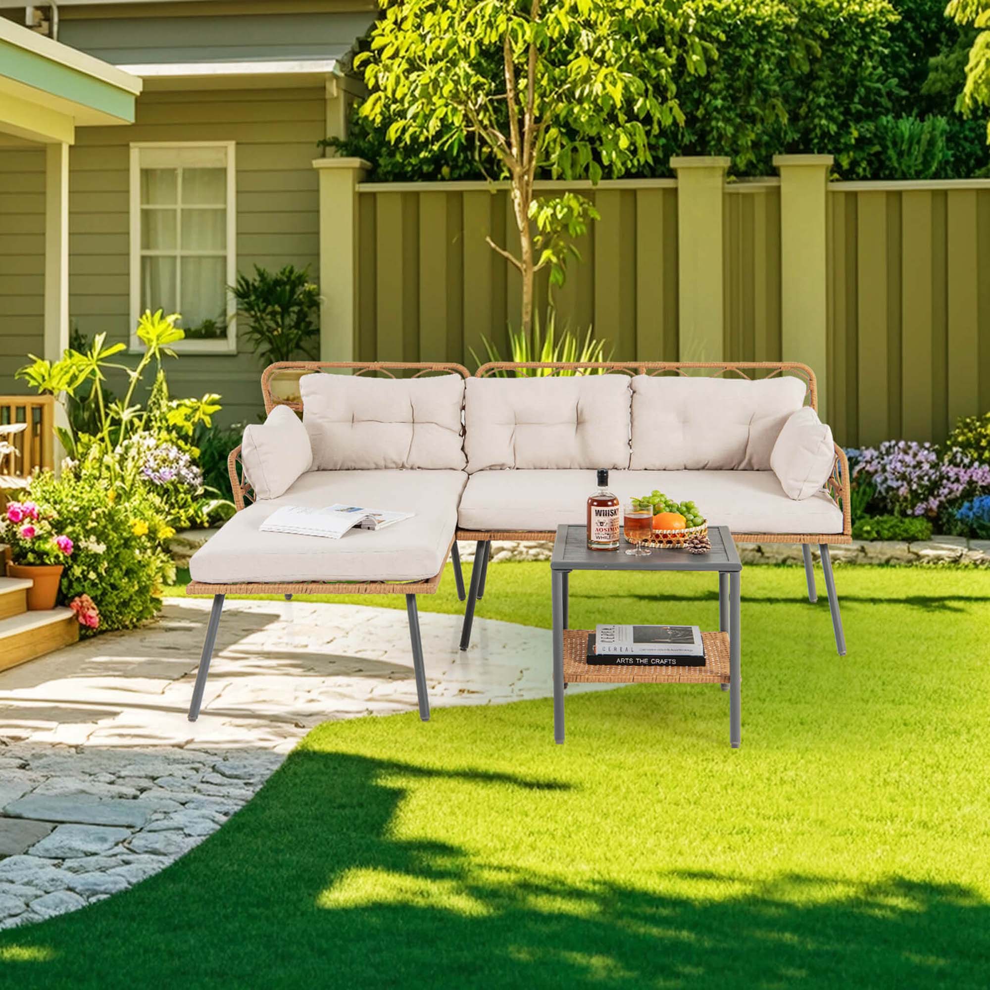 The image shows a backyard with a patio set up. There is a white couch placed on the grass, along with a table and a laptop. The table also has a bottle and some fruit on it. The backyard is surrounded by a fence and features a potted plant and a tree. The scene is likely set up for a relaxing outdoor experience, possibly for working or enjoying leisure time.