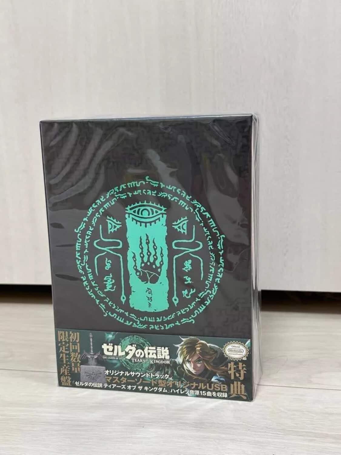 Sure, here is the corrected and grouped text from the image:

---

**Top Section:**

- 5 m SS arsef K A 36 Y 3k L M I S5 J AA se5 E aeys Ocn TEARS KINGDOM USB 15

**Main Text on the Box:**

- ゼルダの伝説 ハイレゾ音源15曲を収録
- オリジナルUSBメモリ
- マスターソード型USBメモリ
- ゼルダの伝説 ハイレゾ音源15曲を収録
- 限定生産
- 初回生産
- 特典

**Additional Text:**

- TEARS OF THE KINGDOM
- Official Nintendo Licensed Product

---

This text is organized based on its appearance on the packaging.