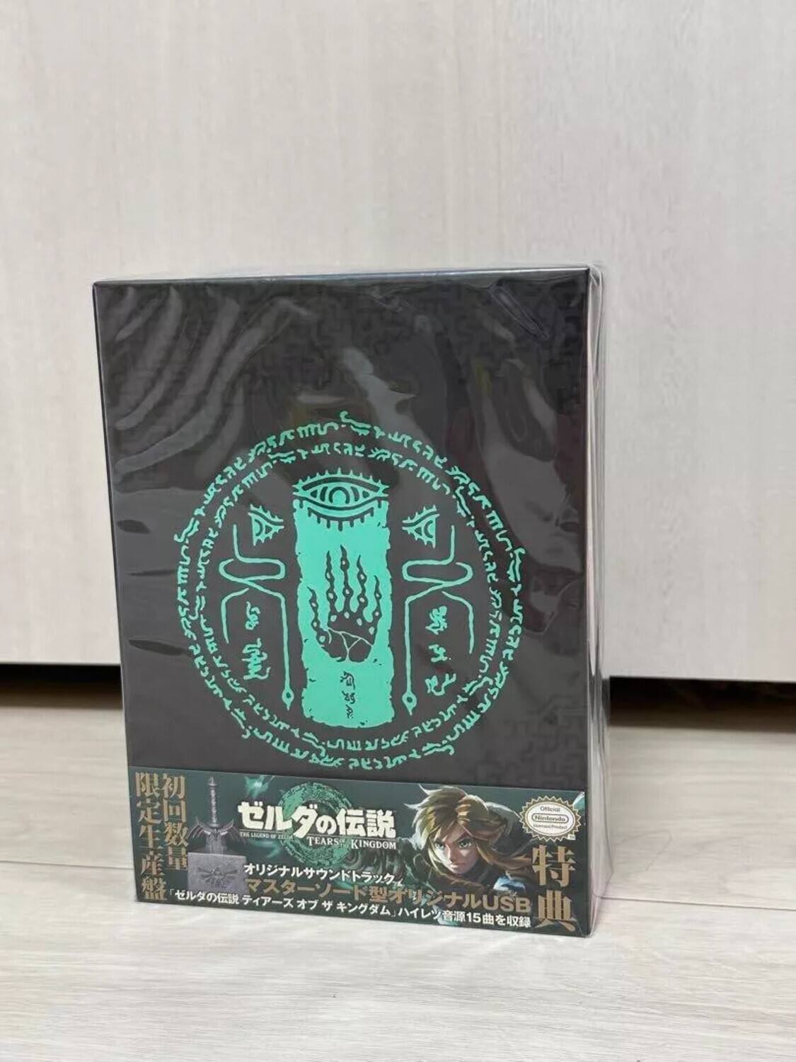 Sure, here is the corrected and grouped text from the image:

---

**Top Section:**

- 5 m SS arsef K A 36 Y 3k L M I S5 J AA se5 E aeys Ocn TEARS KINGDOM USB 15

**Main Text on the Box:**

- ゼルダの伝説 ハイレゾ音源15曲を収録
- オリジナルUSBメモリ
- マスターソード型USBメモリ
- ゼルダの伝説 ハイレゾ音源15曲を収録
- 限定生産
- 初回生産
- 特典

**Additional Text:**

- TEARS OF THE KINGDOM
- Official Nintendo Licensed Product

---

This text is organized based on its appearance on the packaging.