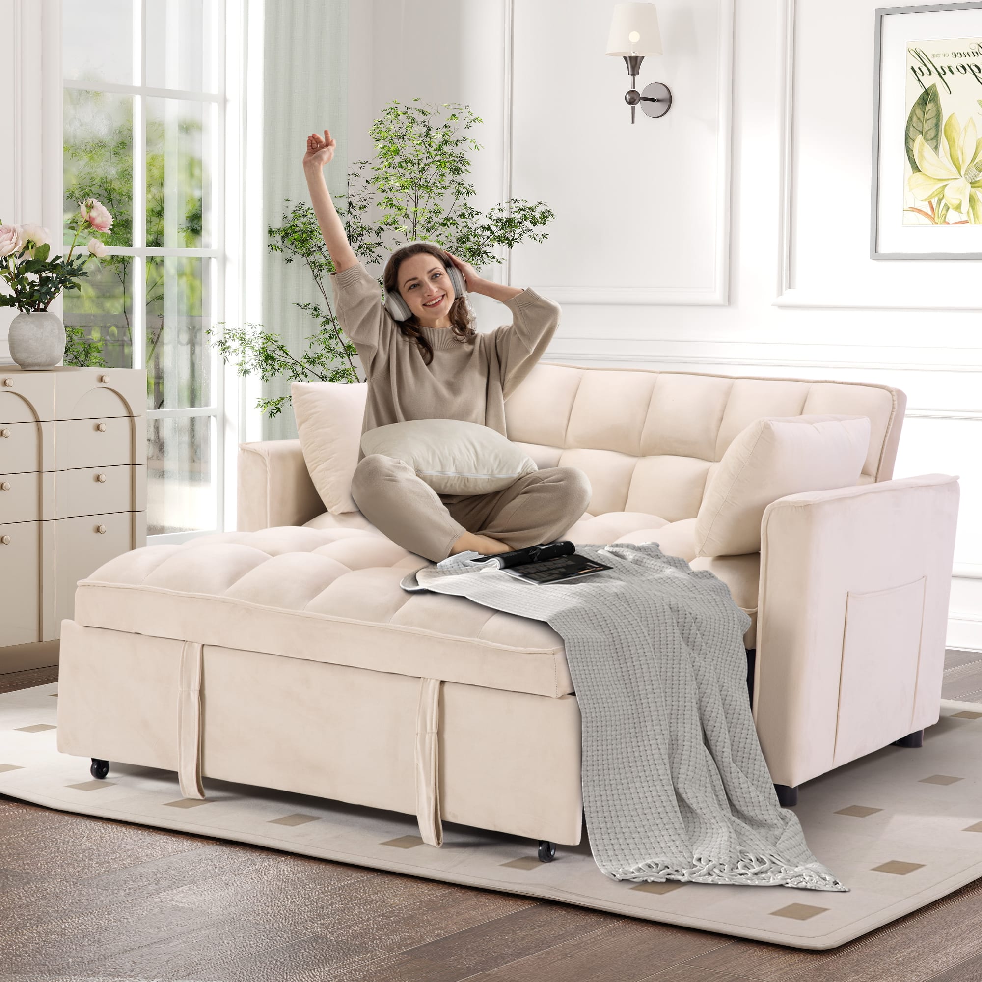 The image shows a woman sitting on a couch, wearing a grey outfit, and holding a remote control. She is smiling and appears to be enjoying herself. The couch is positioned in a living room, with a potted plant nearby. The room also features a rug, adding to the cozy atmosphere.