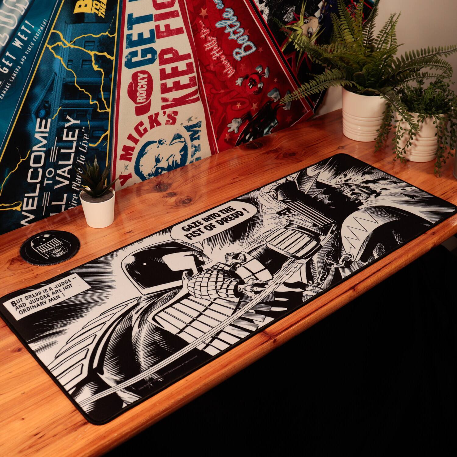 Sure, here is the corrected and grouped text from the image:

---

**Left Poster:**
- "WELCOME TO LL VALLEY"
- "BUT DREDD IS A JUDGE - JUDGES ARE NOT ORDINARY MEN!"

**Middle Poster:**
- "GET ROCKY"
- "KEEP FIGHTING"
- "MICK'S FIRST WOOD!"

**Right Poster:**
- "BROOKLYN"
- "BROOKLYN"

**Rug:**
- "GAZE INTO THE FIST OF DREDD!"

---

This should accurately reflect the text from the image.