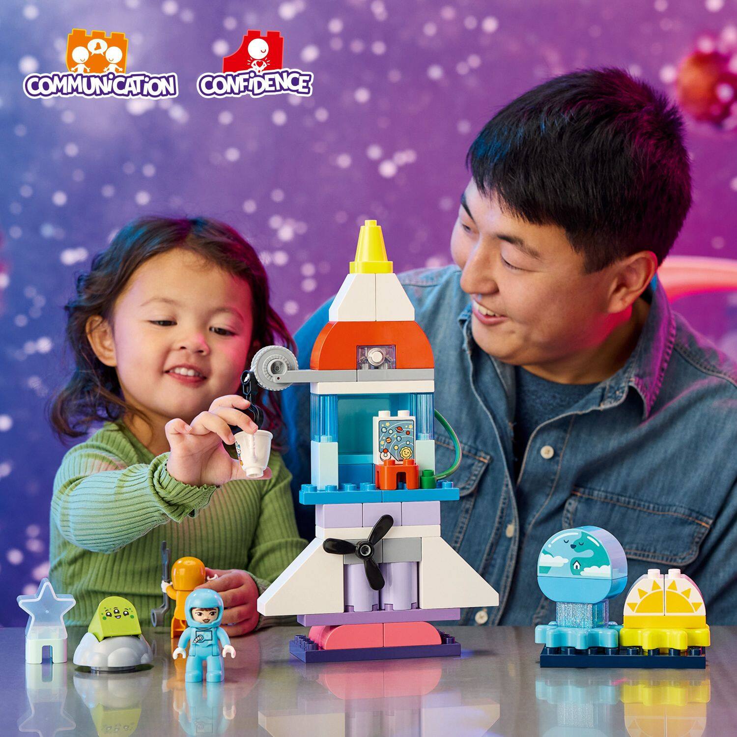 The image shows a man and a young girl playing with a toy rocket ship. The man is smiling as the little girl holds a toy rocket, and they are both enjoying their time together. The scene takes place on a table where the toy rocket ship is placed. The toy rocket is a prominent feature in the image, and the man and the girl are the main subjects of the scene.