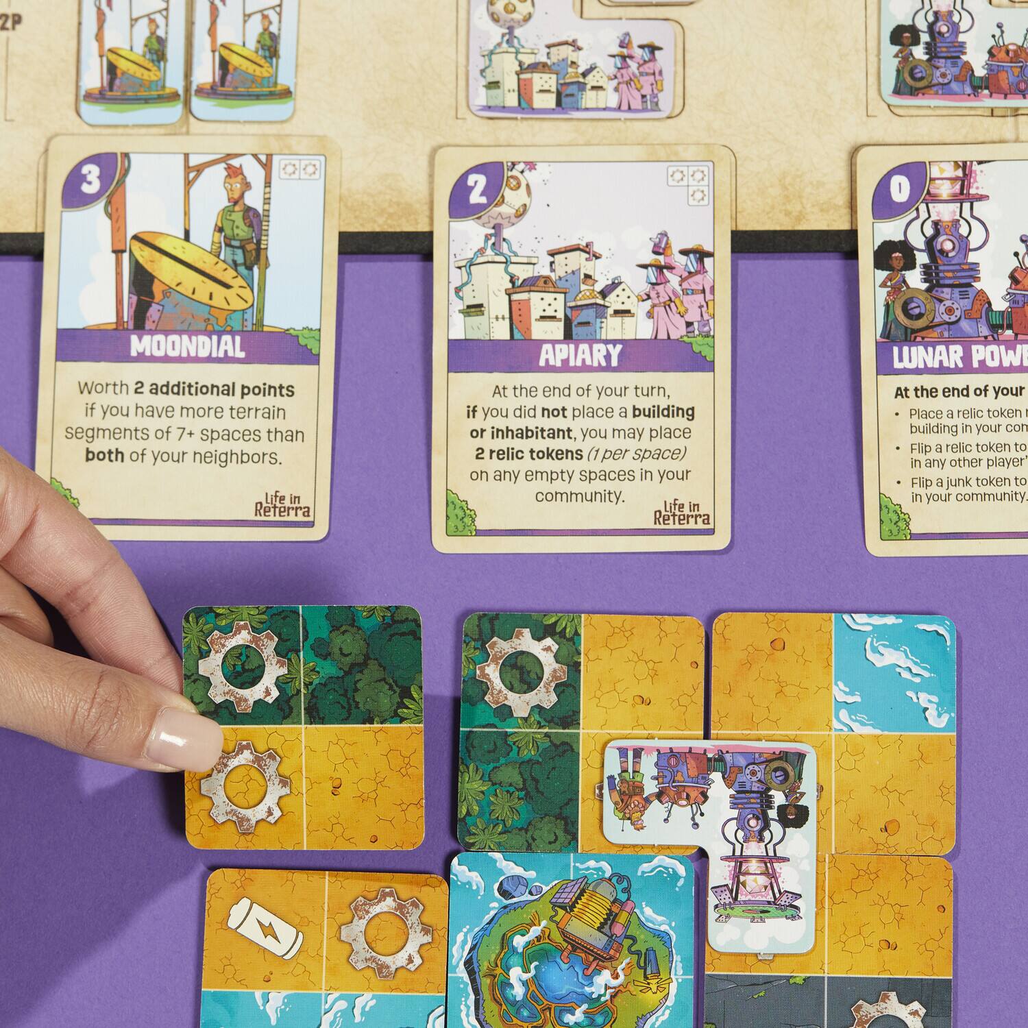 MOONDIAL  
Worth 2 additional points if you have more terrain segments of 7+ spaces than both of your neighbors.  
Life in Reterra  

APIARY  
At the end of your turn, if you did not place a building or inhabitant, you may place 2 relic tokens (1 per space) on any empty spaces in your community.  
Life in Reterra  

LUNAR POWER  
At the end of your turn:  
- Place a relic token in any other player's building in your community.  
- Flip a relic token to in any other player's community.  
- Flip a junk token to in your community.  
Life in Reterra