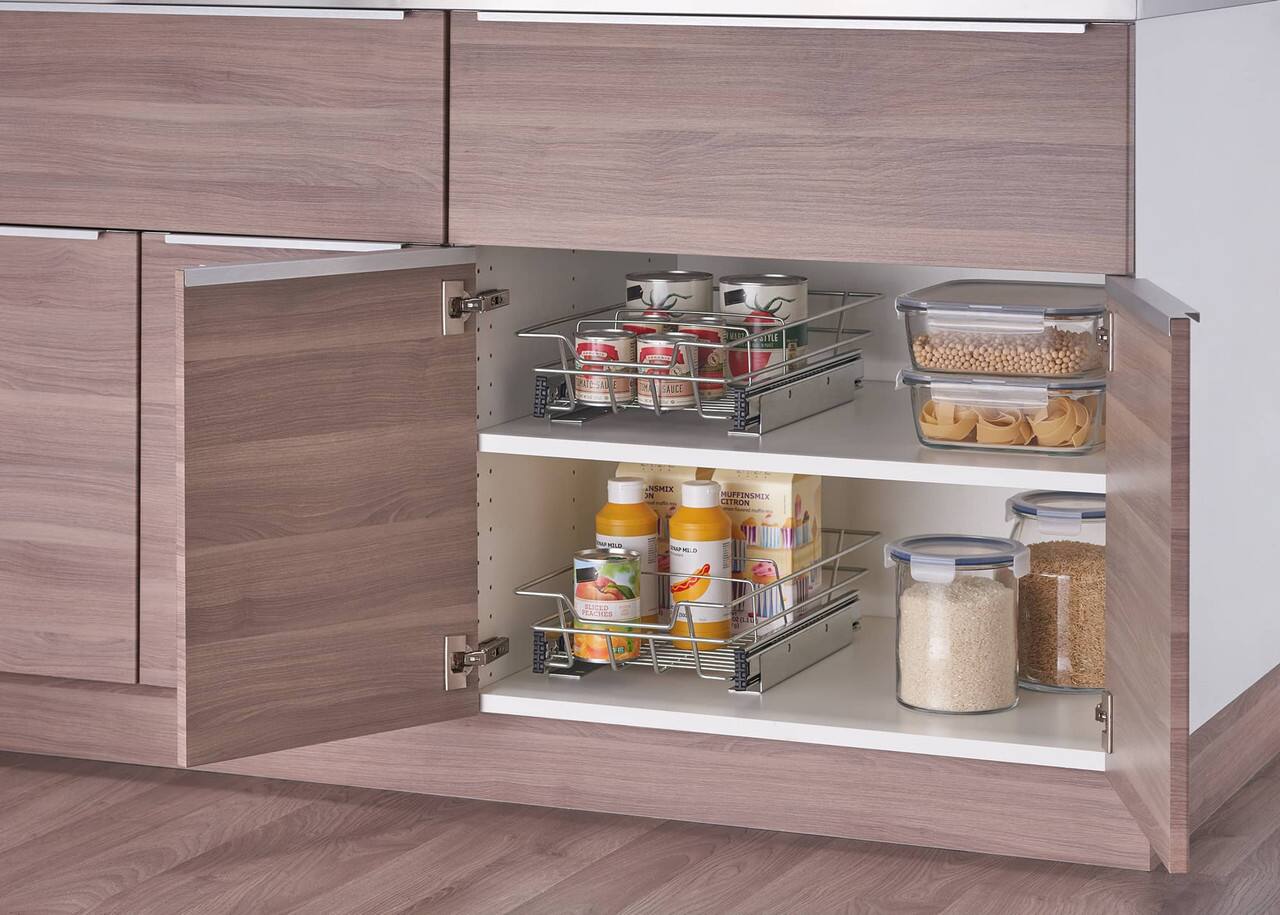 The image shows a kitchen with a wooden cabinet that has a drawer open, revealing various food items. The drawer is filled with different types of food, including a mix of ingredients and containers. There are several bottles, a bowl, and a cup placed within the drawer. The cabinet appears to be well-organized, making it easy to find and access the food items when needed.